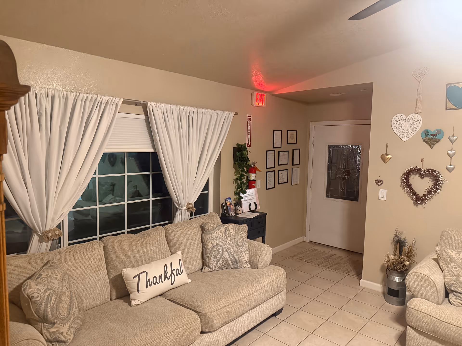 Cozy living room with beige sofa, white curtains, and decorative wall accents.