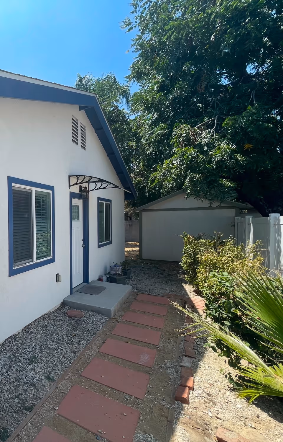 White building with blue trim and a gravel path leading to a door.
