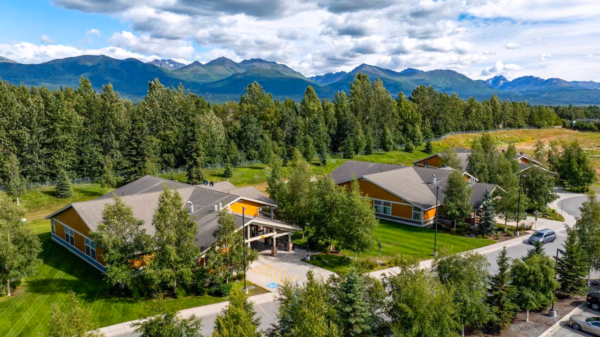 Aerial view of Polaris Extended Care campus amid trees with distant mountains.
