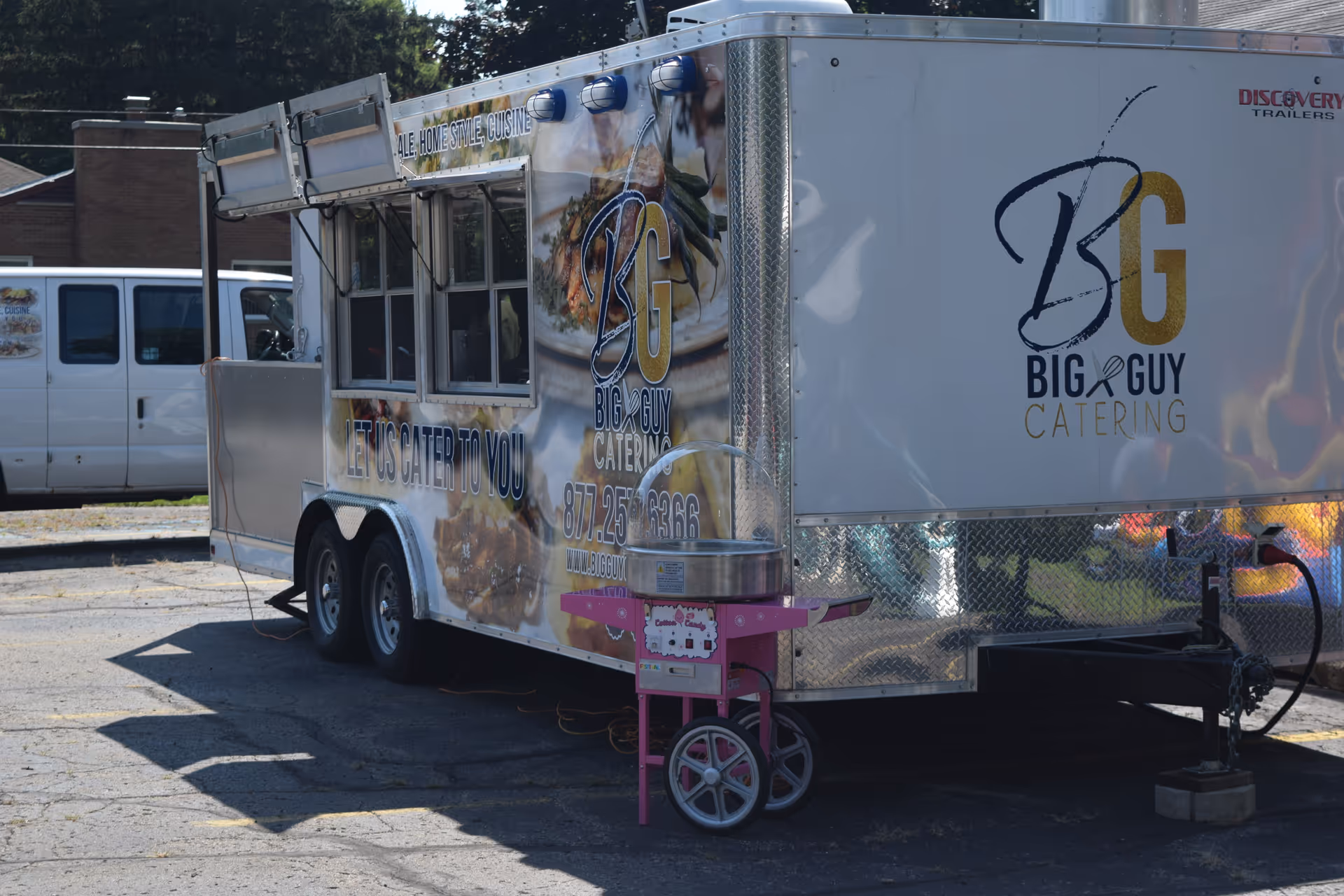 An exterior view of a catering trailer with Big & Guy Catering branding in parking lot.