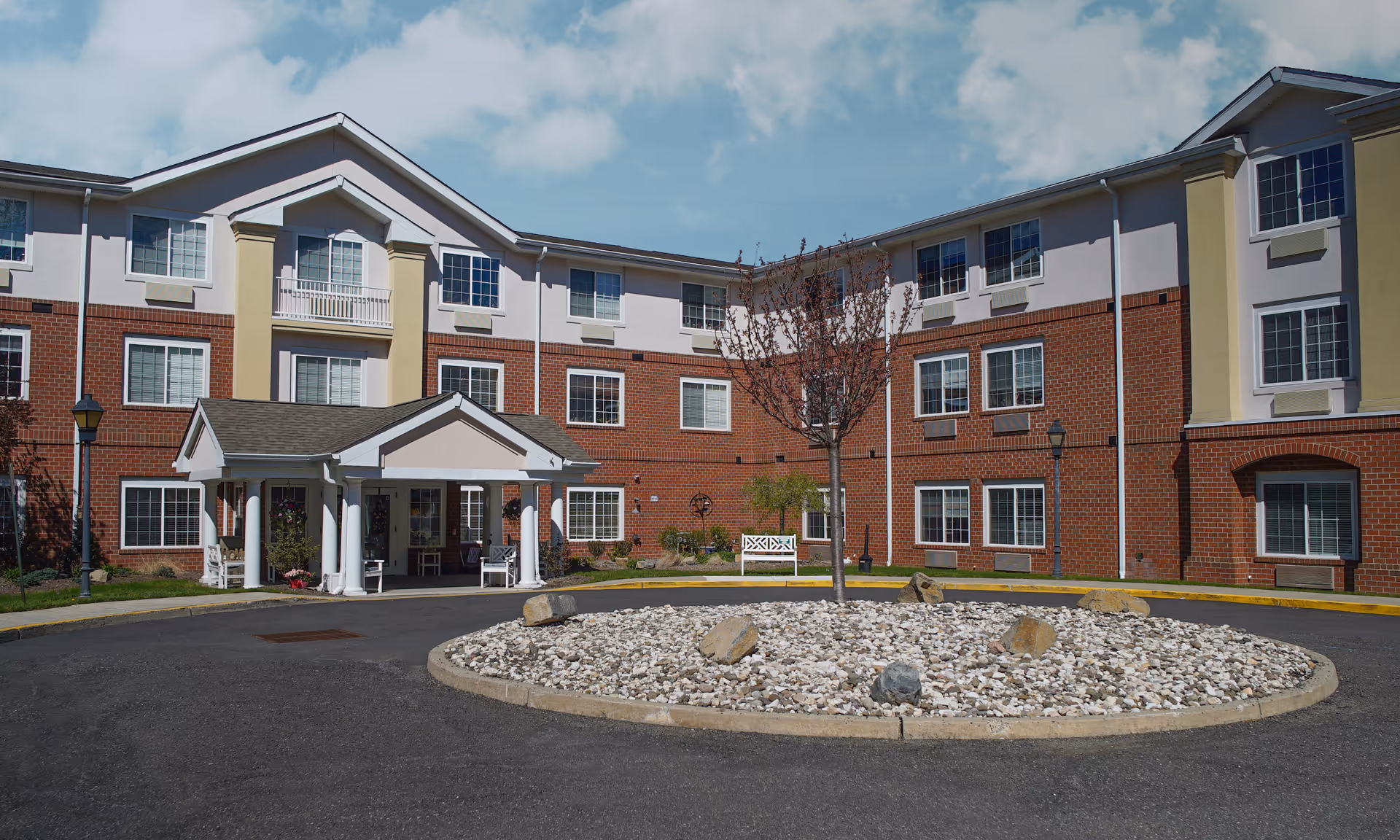 Exterior view of Brookdale Emerson senior living facility entrance with a roundabout and landscaping.
