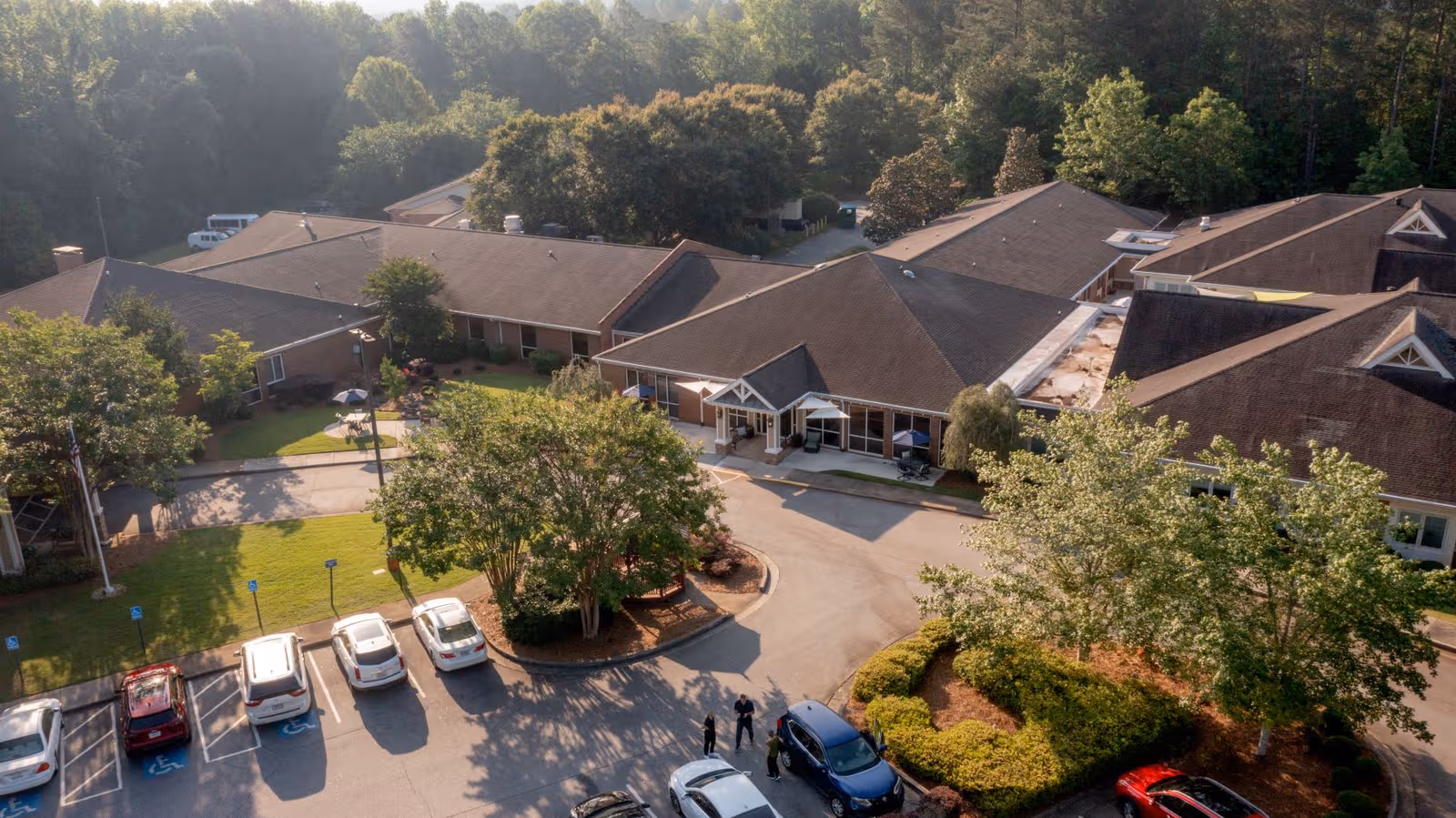 Aerial view of Highland Hills senior living campus with parking and landscaped entrance.