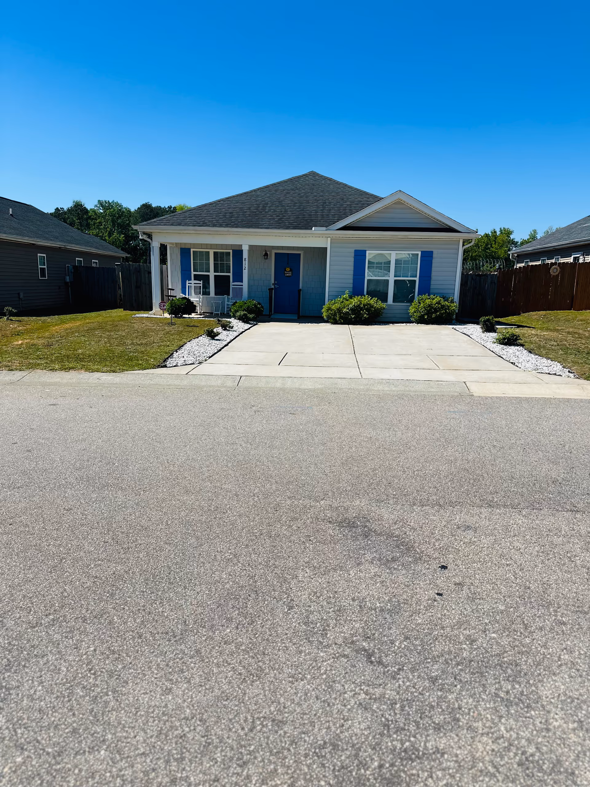 Front view of a single-story house with blue door, blue shutters and landscaped walkway.