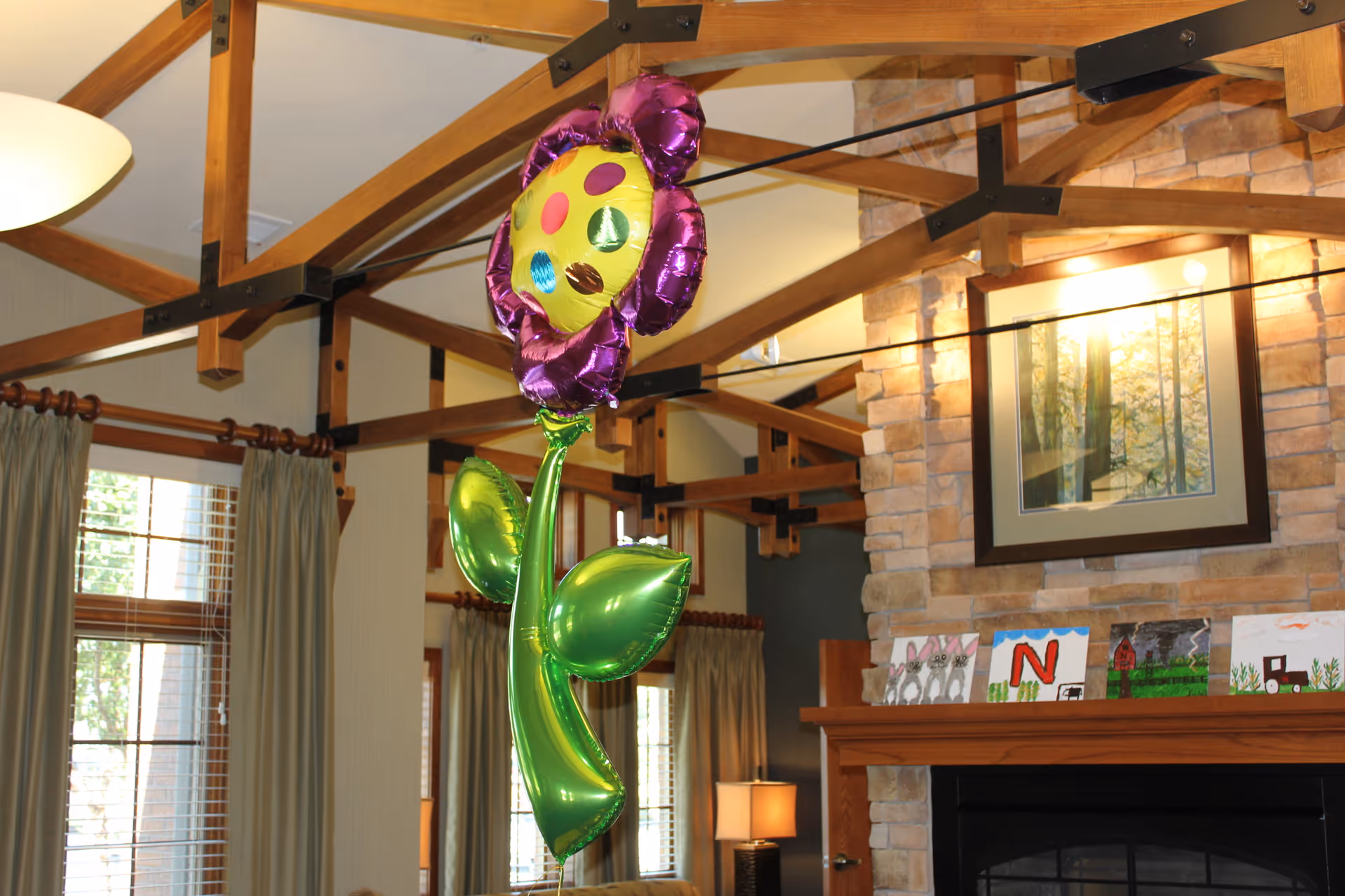 Interior living room with a large purple flower balloon near a stone fireplace.