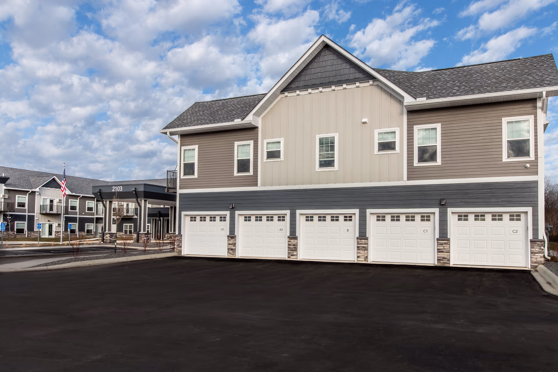 Front view of a two-story senior living facility with row of garage doors and parking.