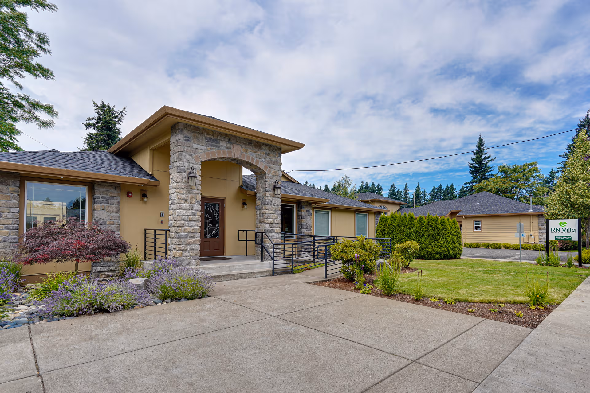 Exterior view of RN Villa Senior Care with stone entryway, ramp, and landscaped front yard.