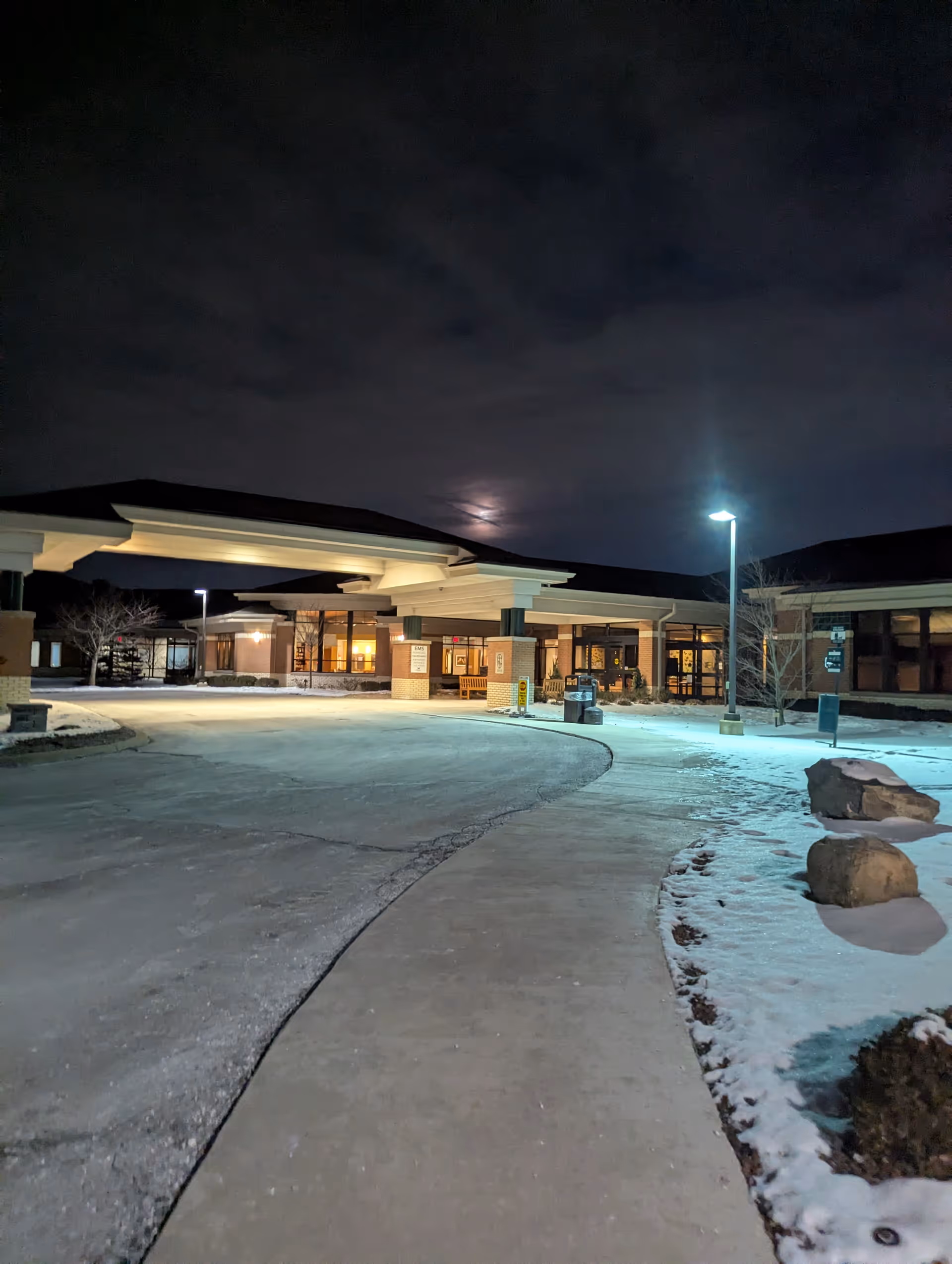 Nighttime exterior of Angela Hospice entrance with curved driveway and illuminated canopies.