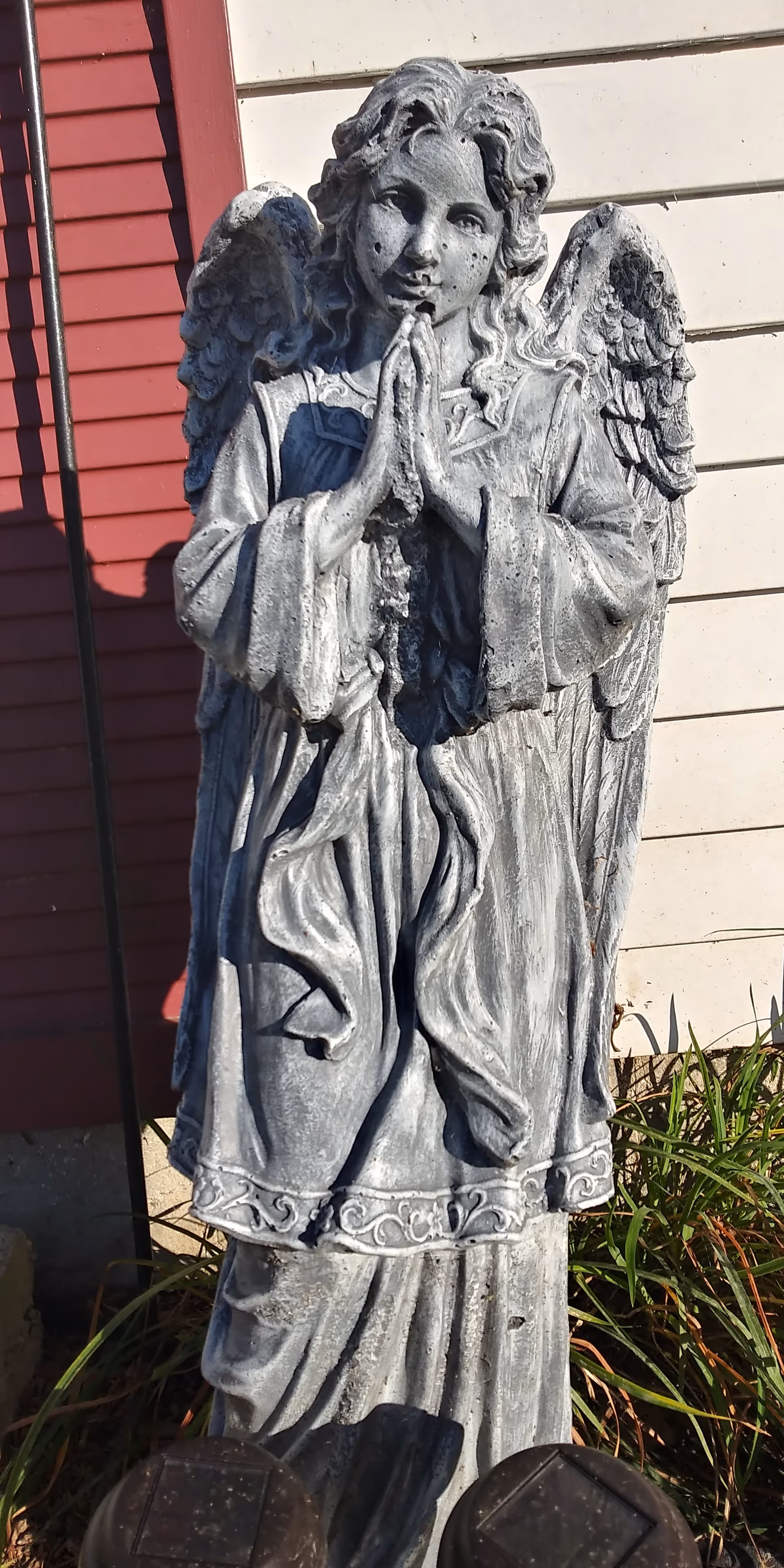 Stone angel statue stands beside the building exterior with red siding.
