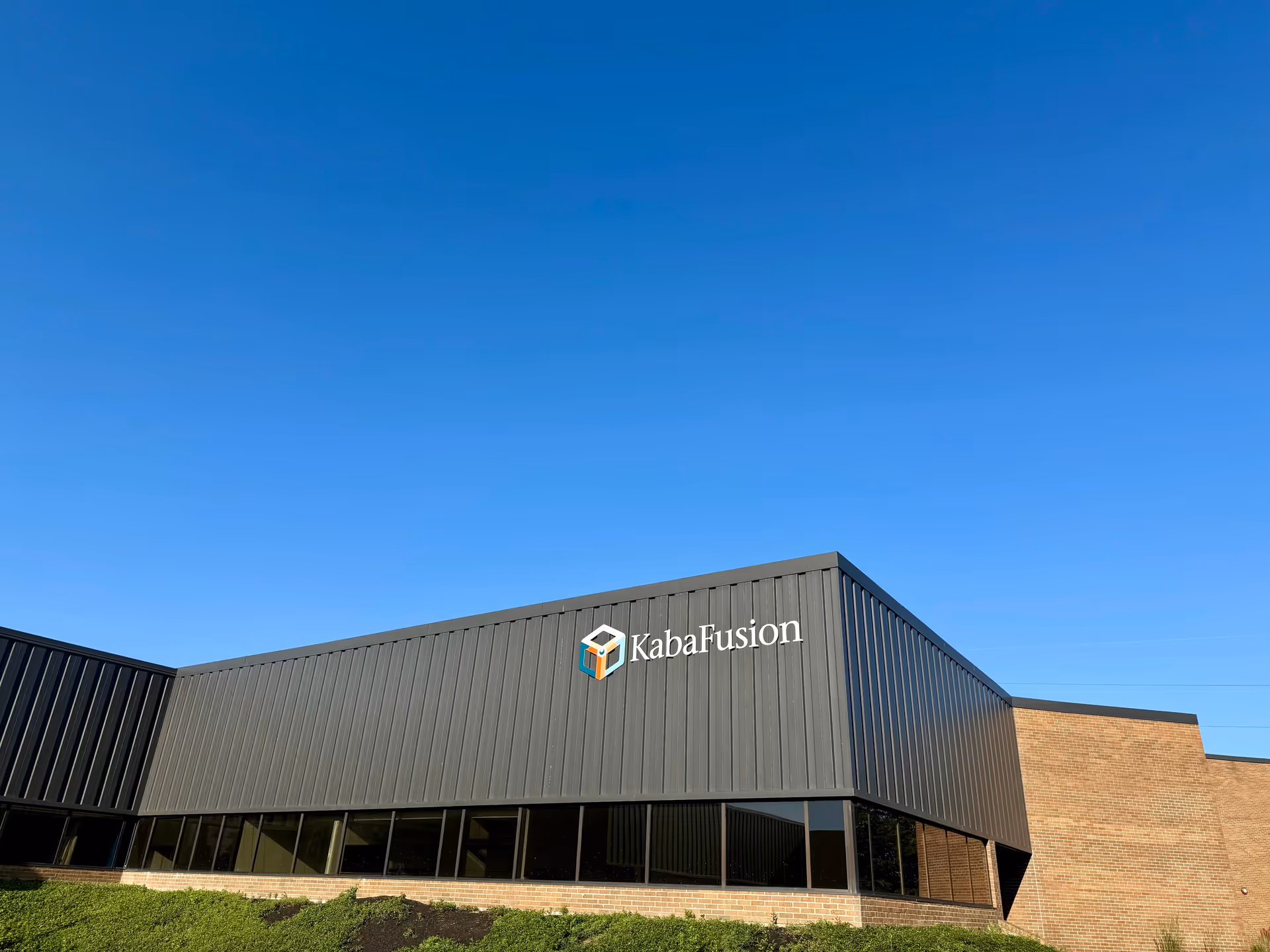Modern facility building exterior with KabaFusion logo under a clear blue sky.