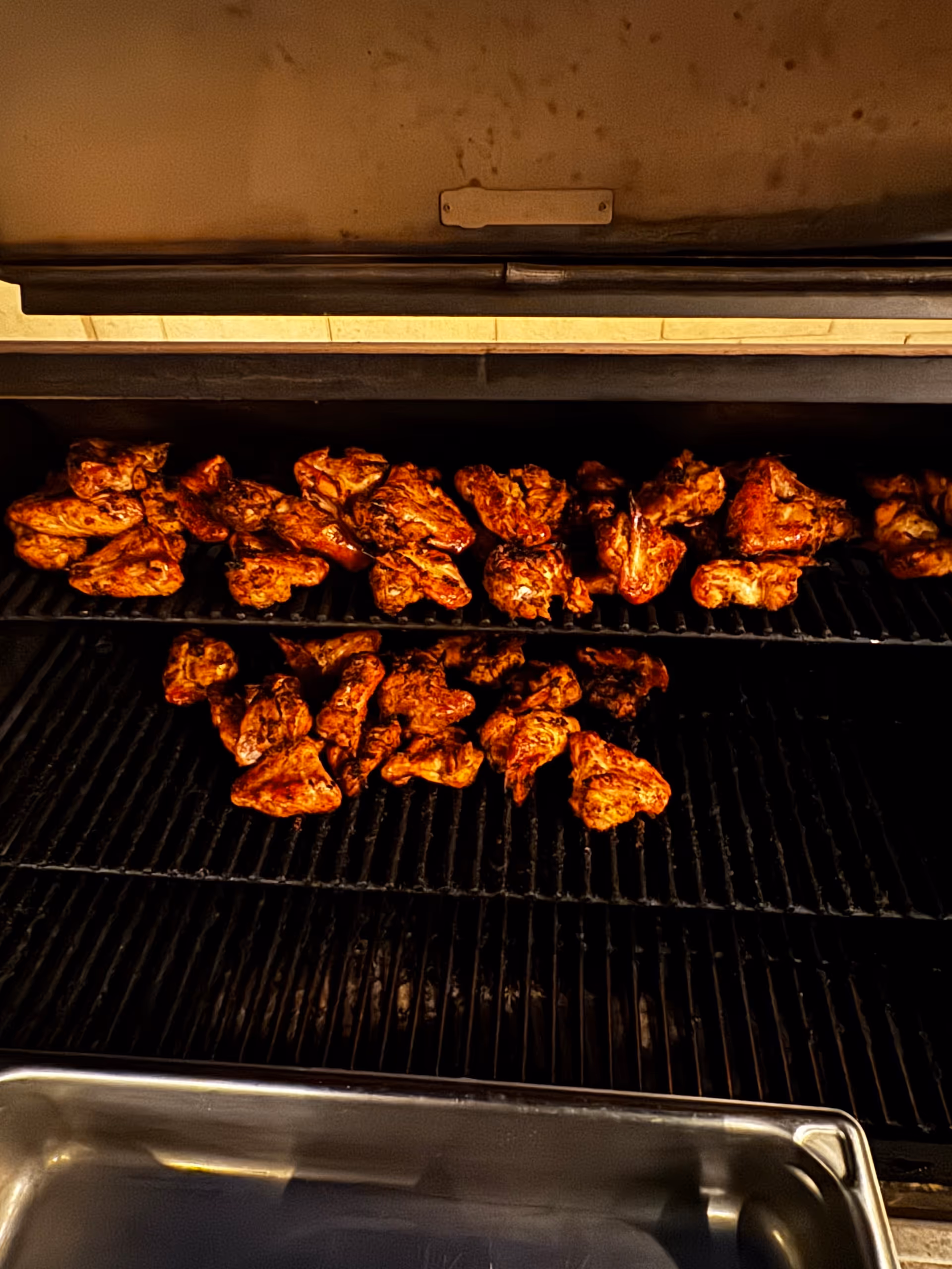 Grilled chicken pieces on a grill inside a kitchen.
