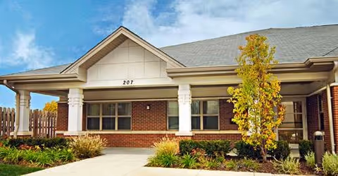 Single-story brick facility exterior with columns and manicured shrubs at entrance.
