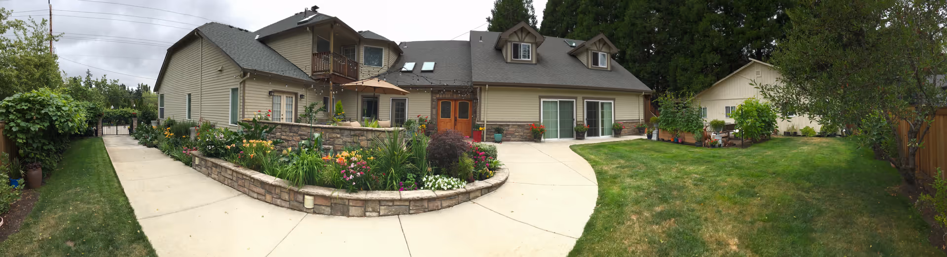Panoramic exterior view of a senior living facility with manicured gardens and curved walkway.