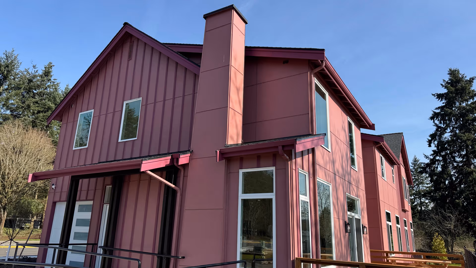 Two-story pink facility exterior with large windows and a modern gabled roof.