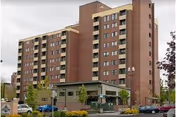 Exterior view of Van Vista senior living building with entrance and parked cars