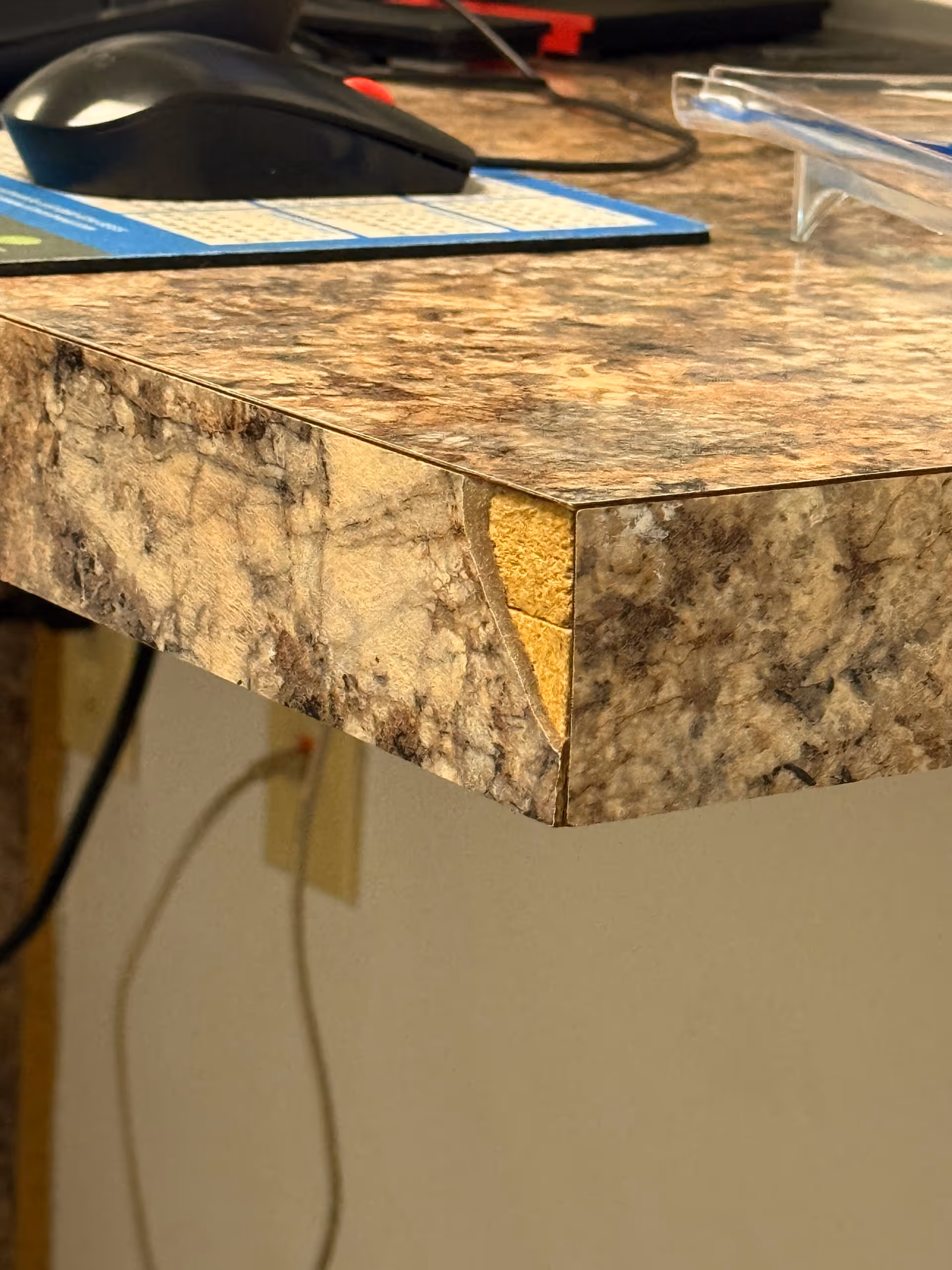 Close-up of a stone countertop edge with a computer mouse nearby.
