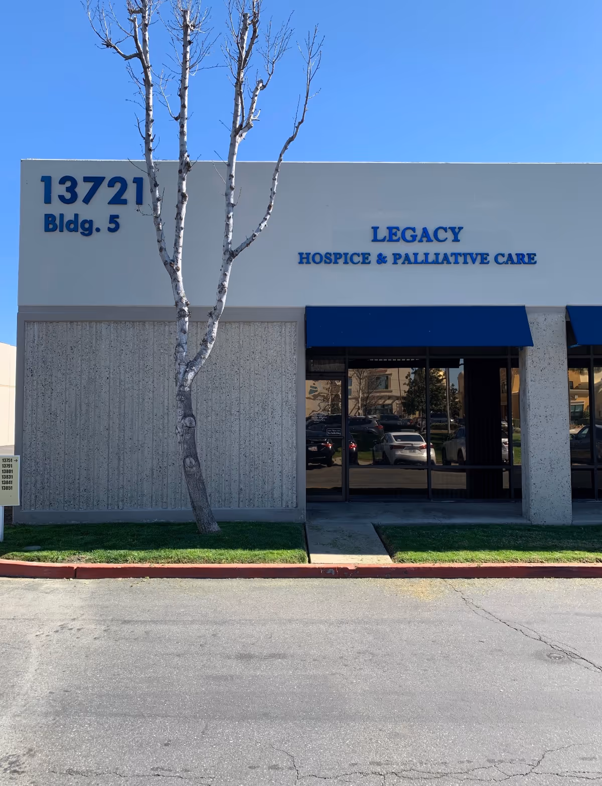 Front exterior of Legacy Hospice and Palliative Care building with blue awnings.