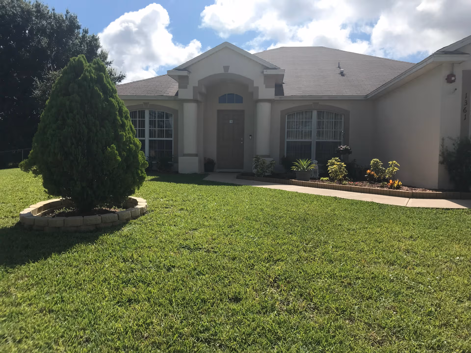 Front exterior of a single-story assisted living facility with a green lawn and landscaping.