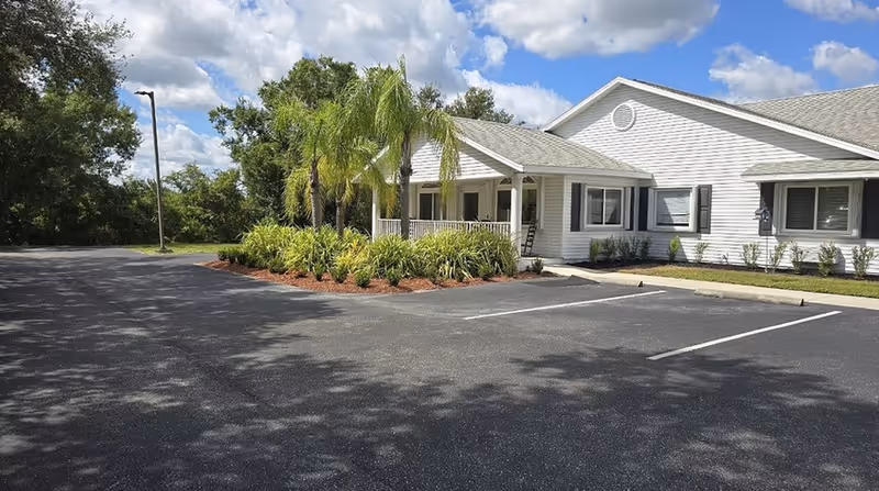 Front view of Arcadia Oaks Assisted Living building with a covered entrance, parking lot, and landscaping.