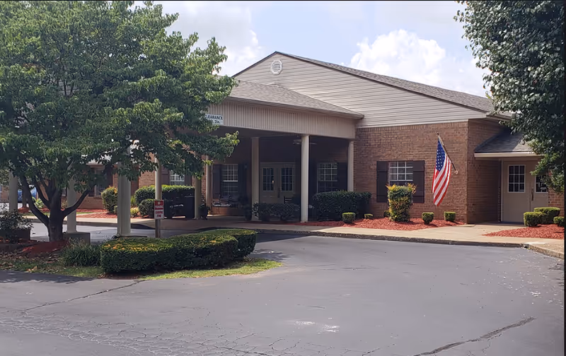 Exterior view of Charter Senior Living of Bowling Green with brick building, entrance, flag, and landscaping.