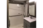 Accessible bathroom with a shower, grab bars, and a vanity in a senior living facility.