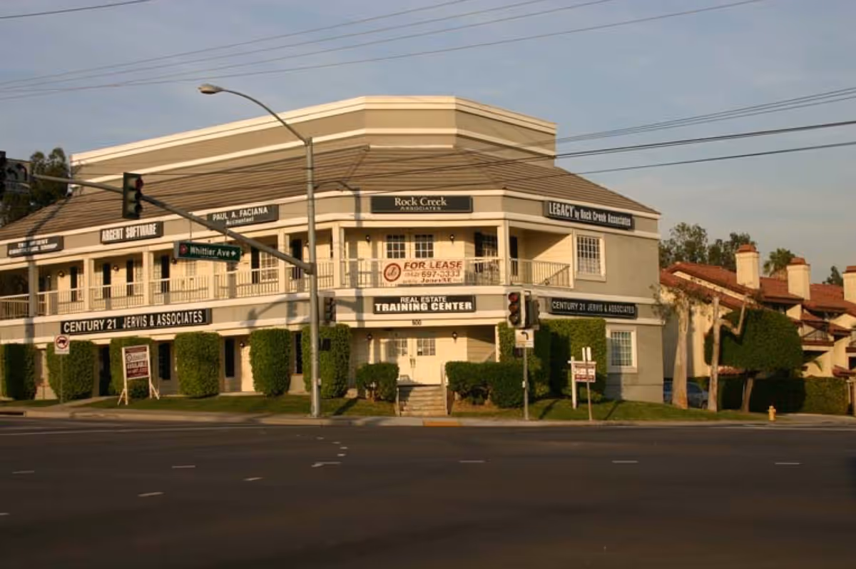 Two-story commercial building with multiple storefronts at a street corner.