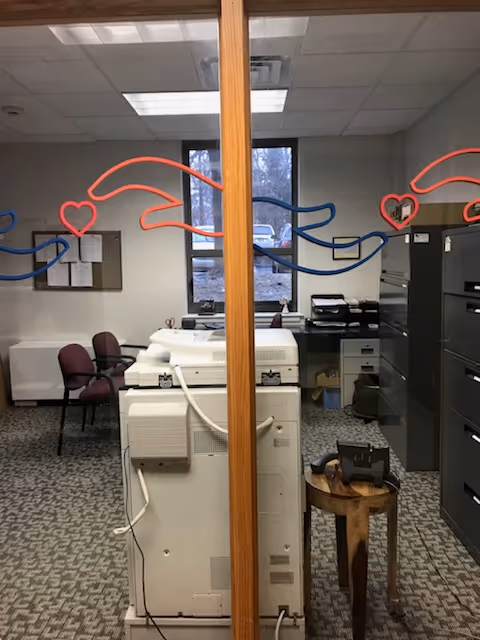 Office area with a copier, filing cabinets, chairs, and glass panels with heart designs.
