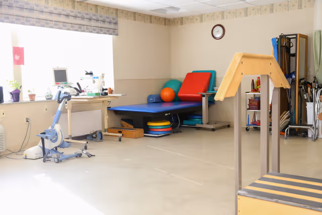 Interior rehabilitation room with exercise equipment, mats, balance beam, and window.