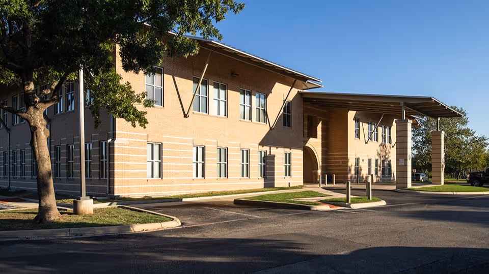Brick two-story facility exterior with a covered entrance and parking.