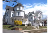 Two white, multi-story retirement homes with porches, steps, and landscaped front yards.