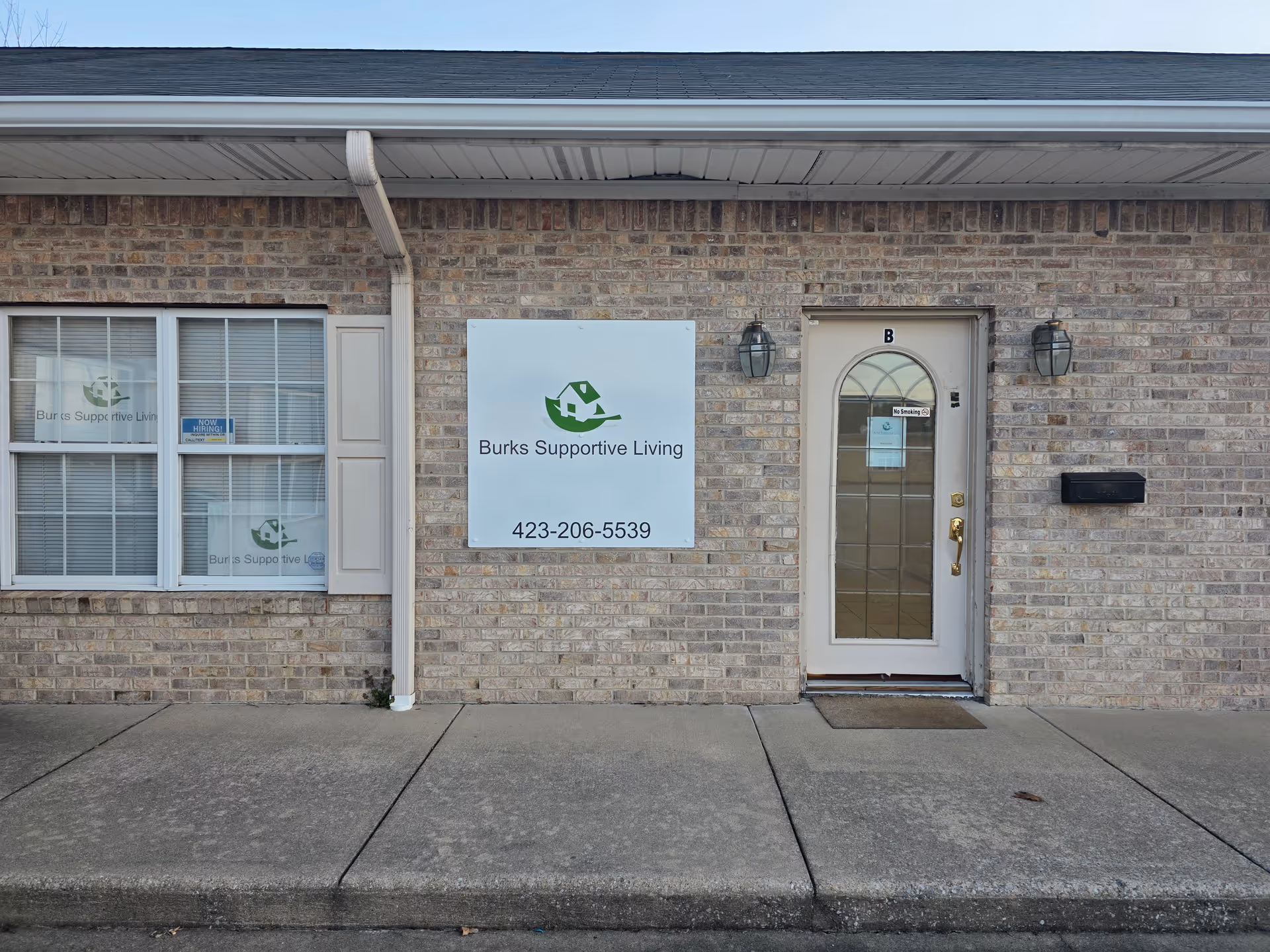 Exterior of Burks Supportive Living with entrance door, window, and sign.