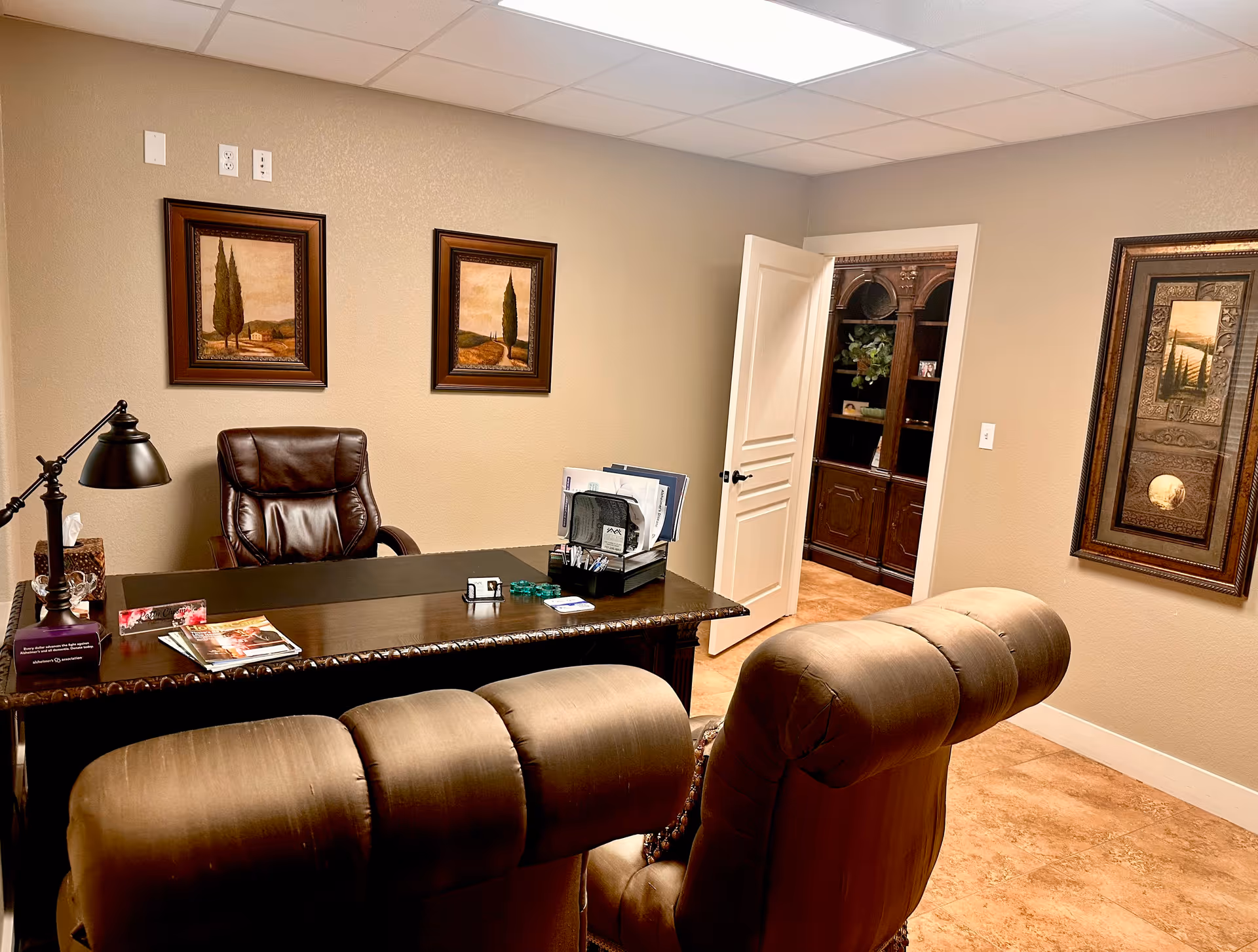 A private office-style reception area with a desk, leather chairs, and wall art.