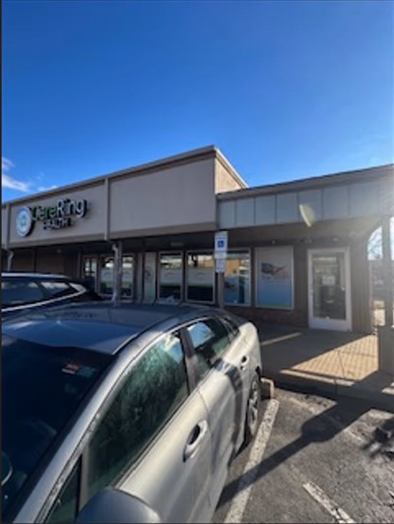 Exterior view of Patriot Home Care building front with parked cars and blue sky
