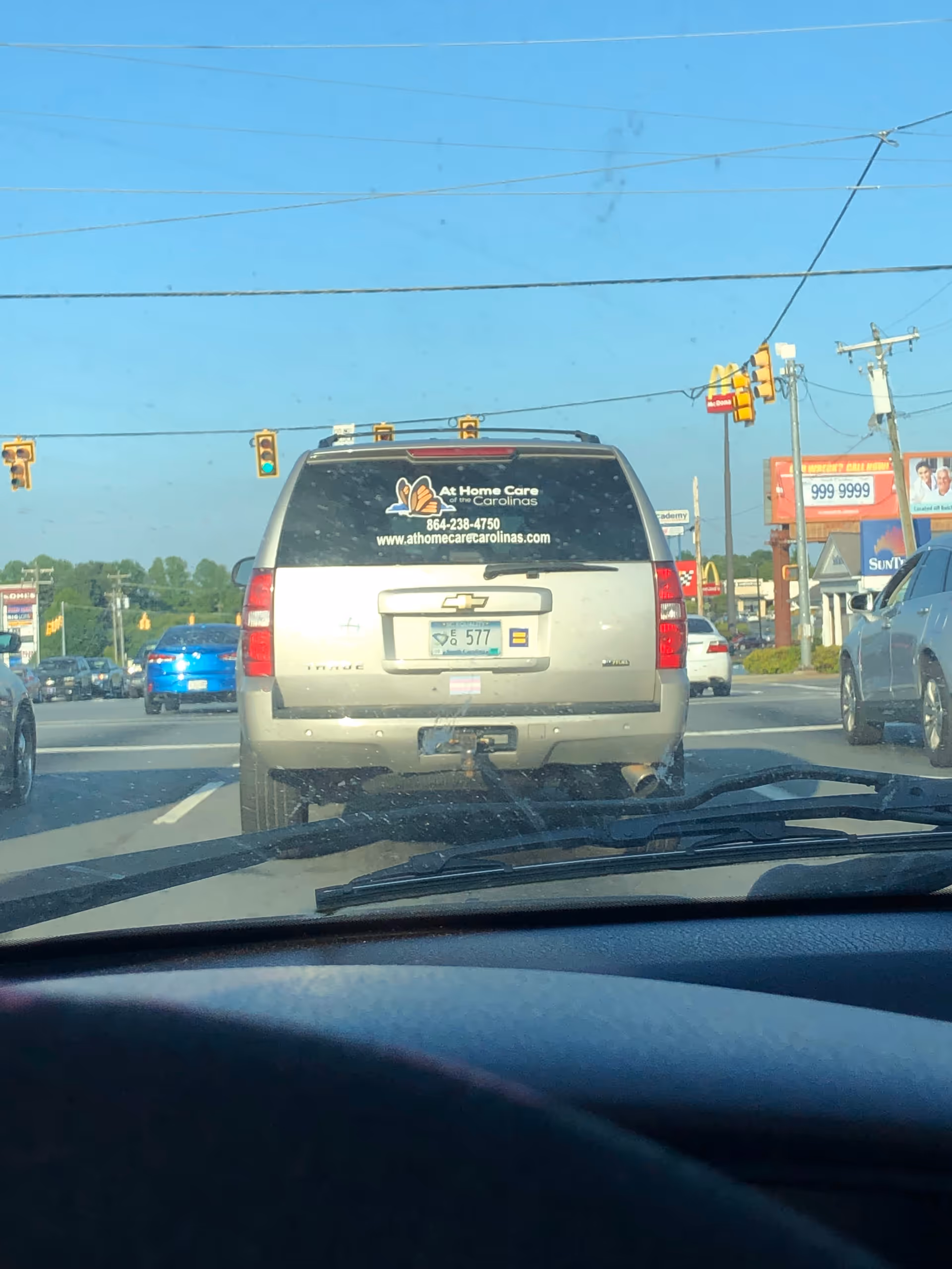 Rear of a silver SUV with At Home Care of the Carolinas sticker at intersection.