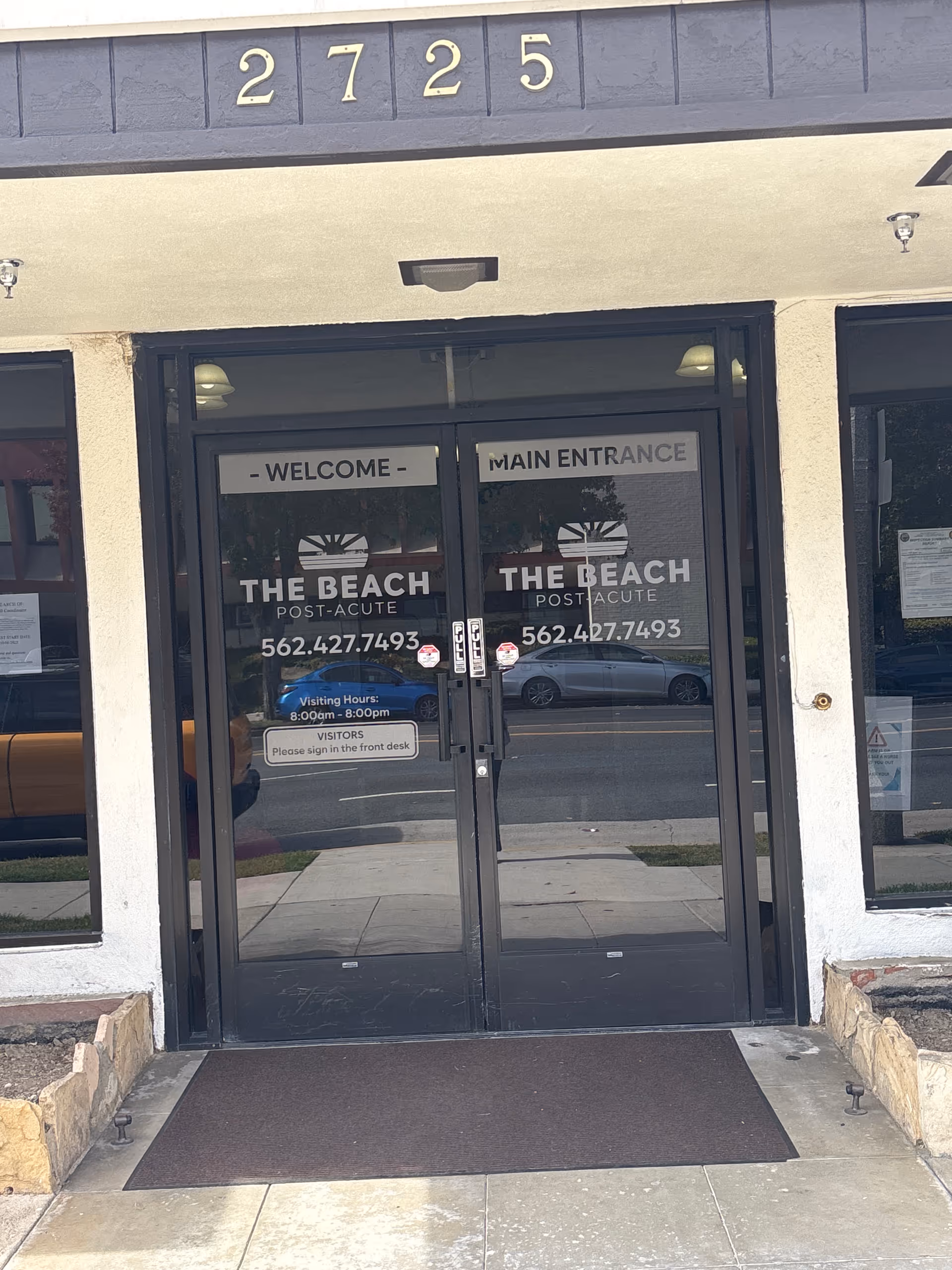 Glass doors show The Beach Post-Acute signage and a welcoming main entrance.