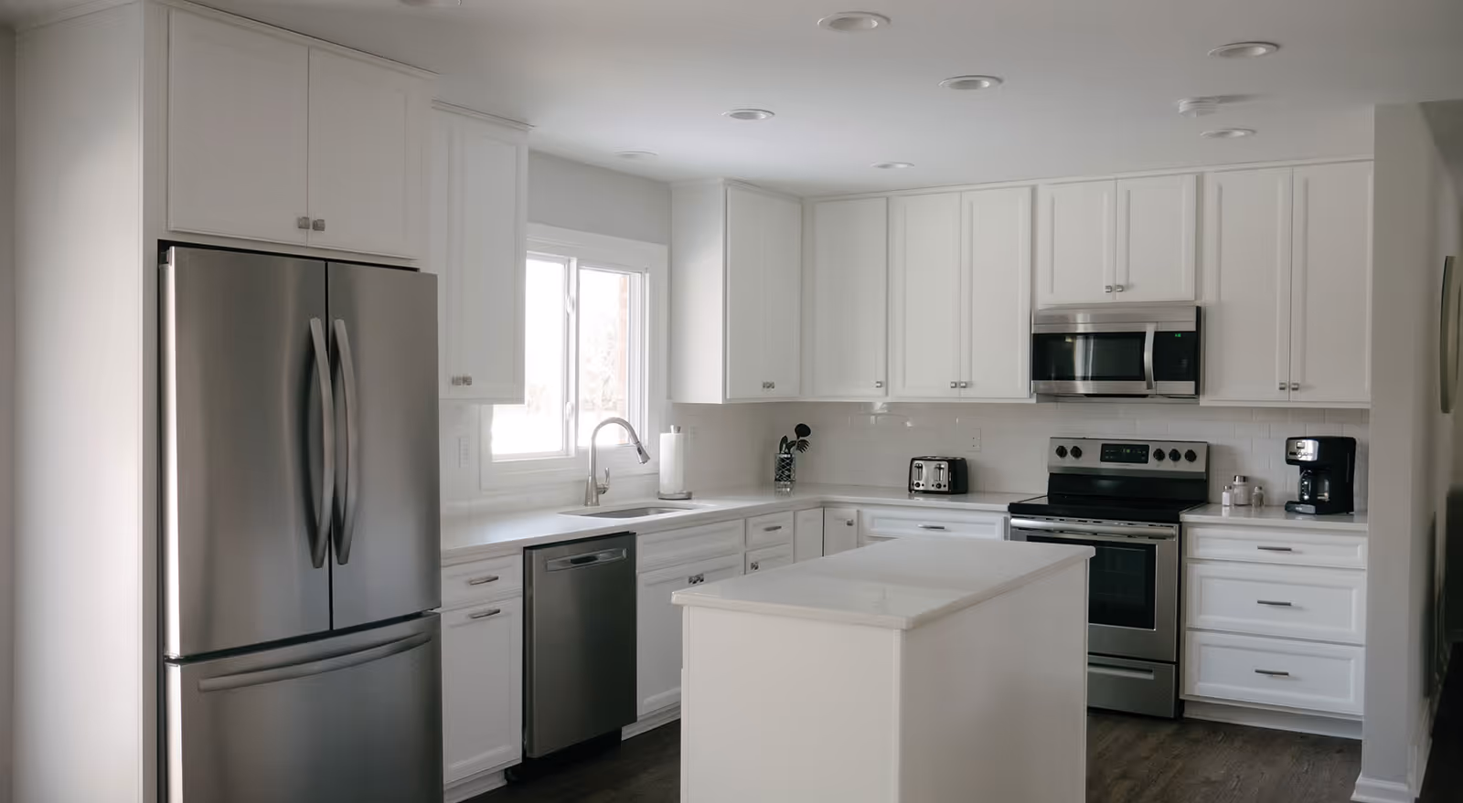 Bright white kitchen with stainless steel appliances, a center island, and ample cabinetry.