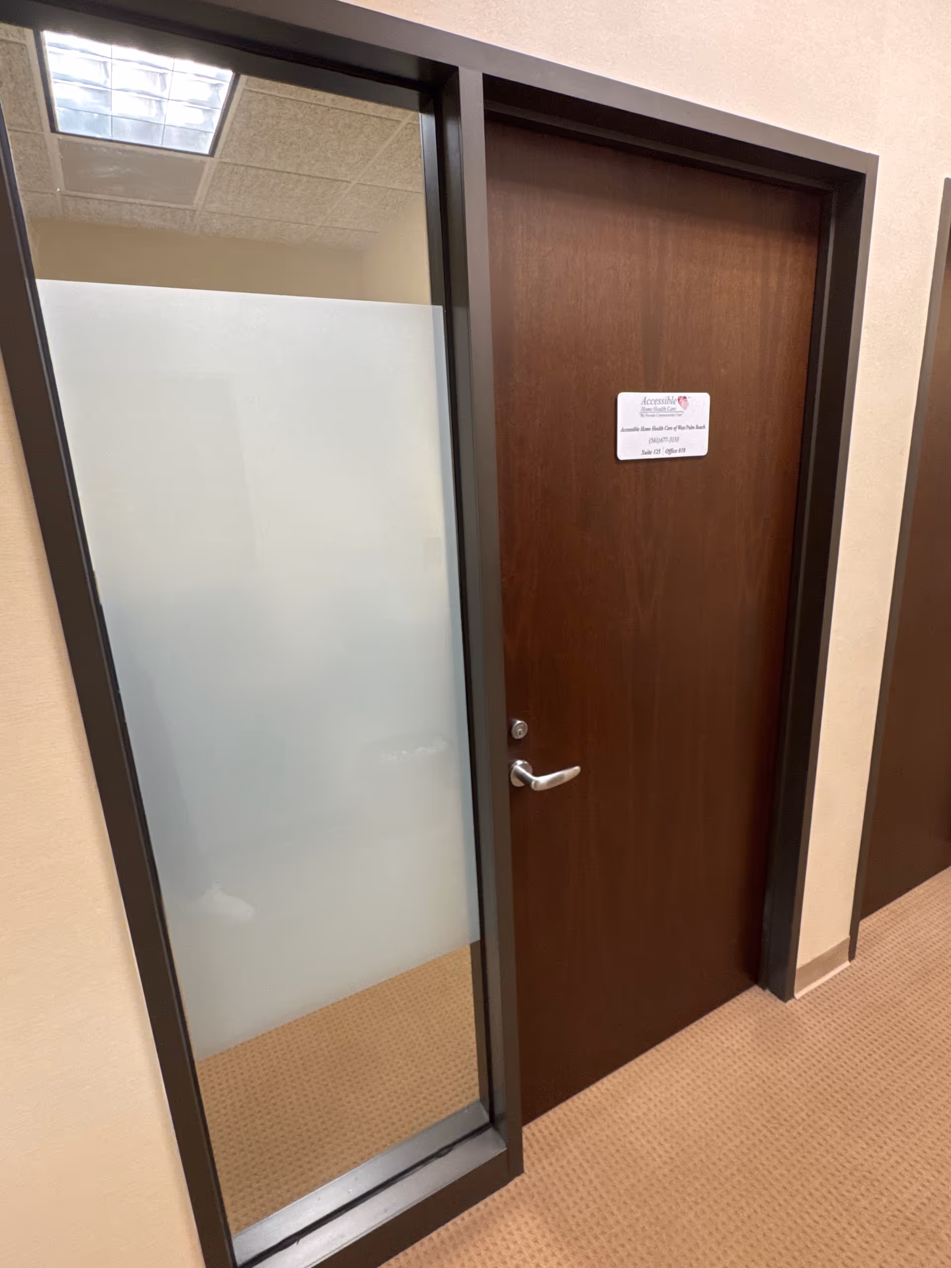 Interior hallway featuring a brown door with frosted glass panel and sign.
