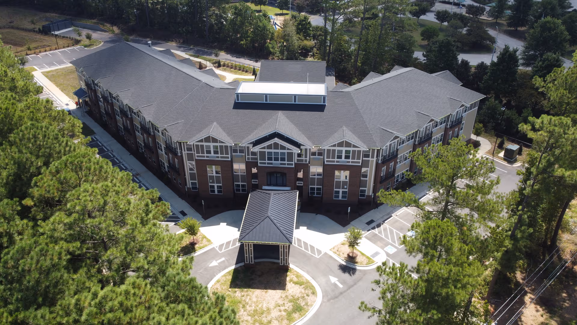 Aerial view of a brick, multi-wing senior living facility with a circular driveway.