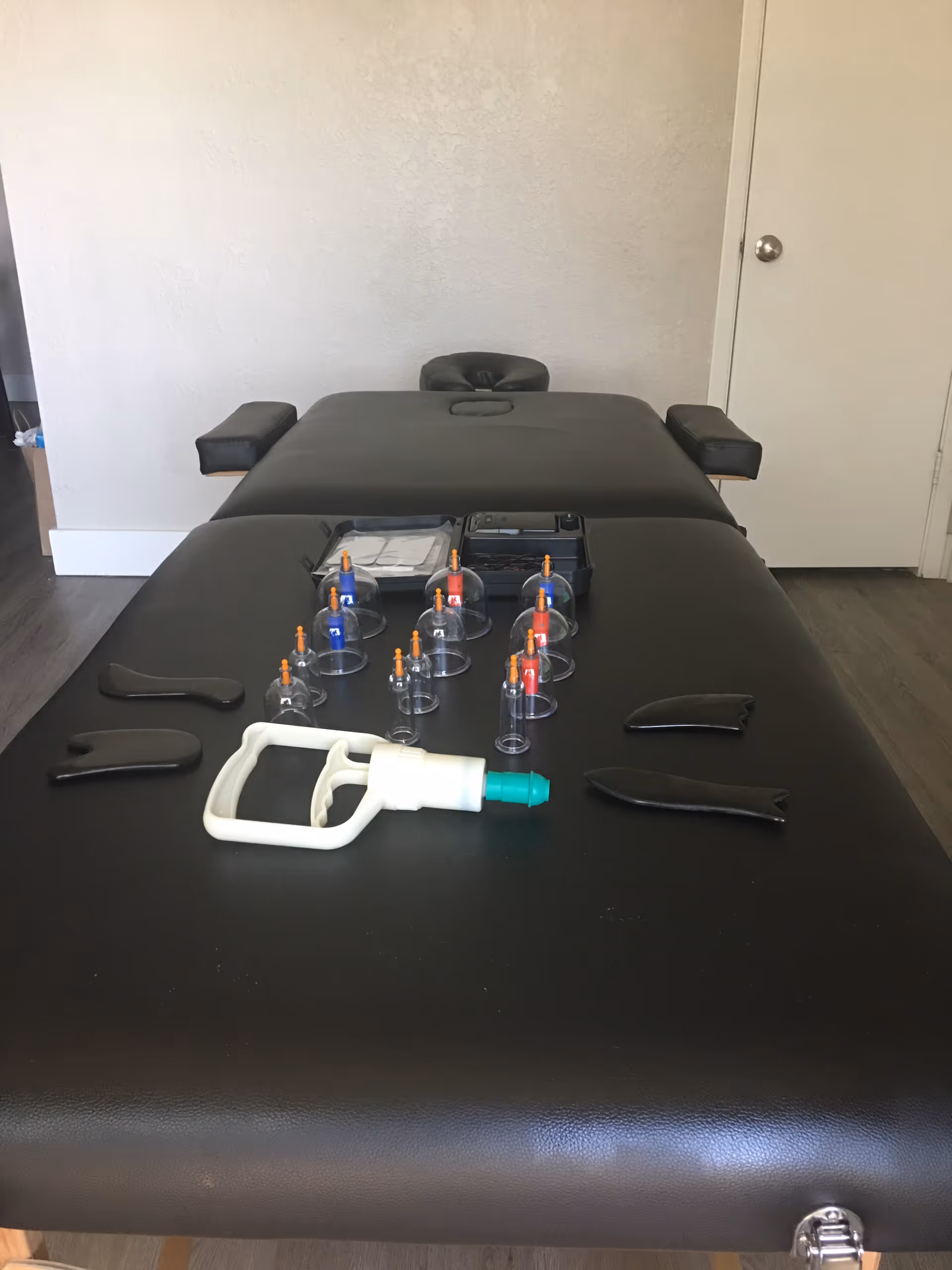 Massage therapy table in a treatment room with cupping cups and suction tool.