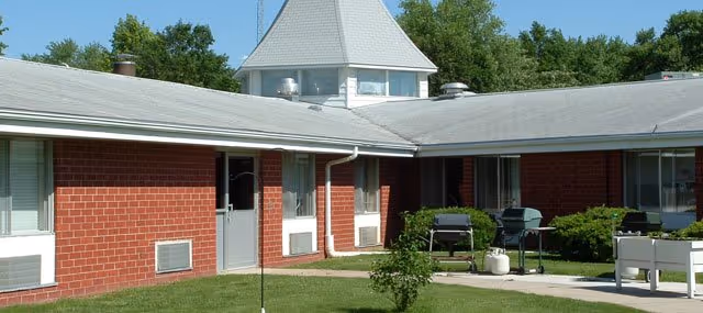 Exterior view of Maxwell House: brick, low-rise facility with lawn and outdoor grills.