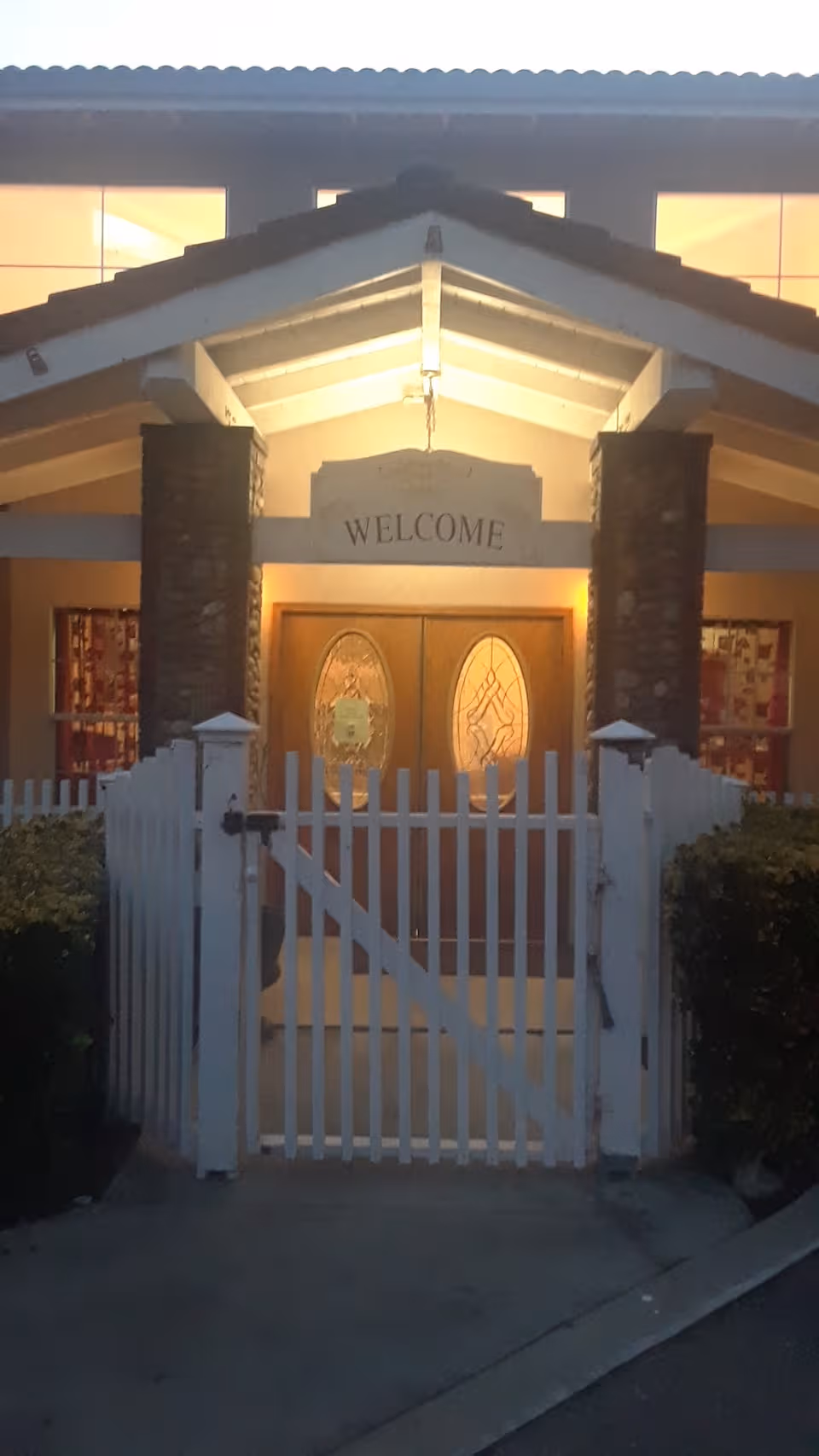 Front entrance of Paradise Assisted Care with a white picket gate and double doors.