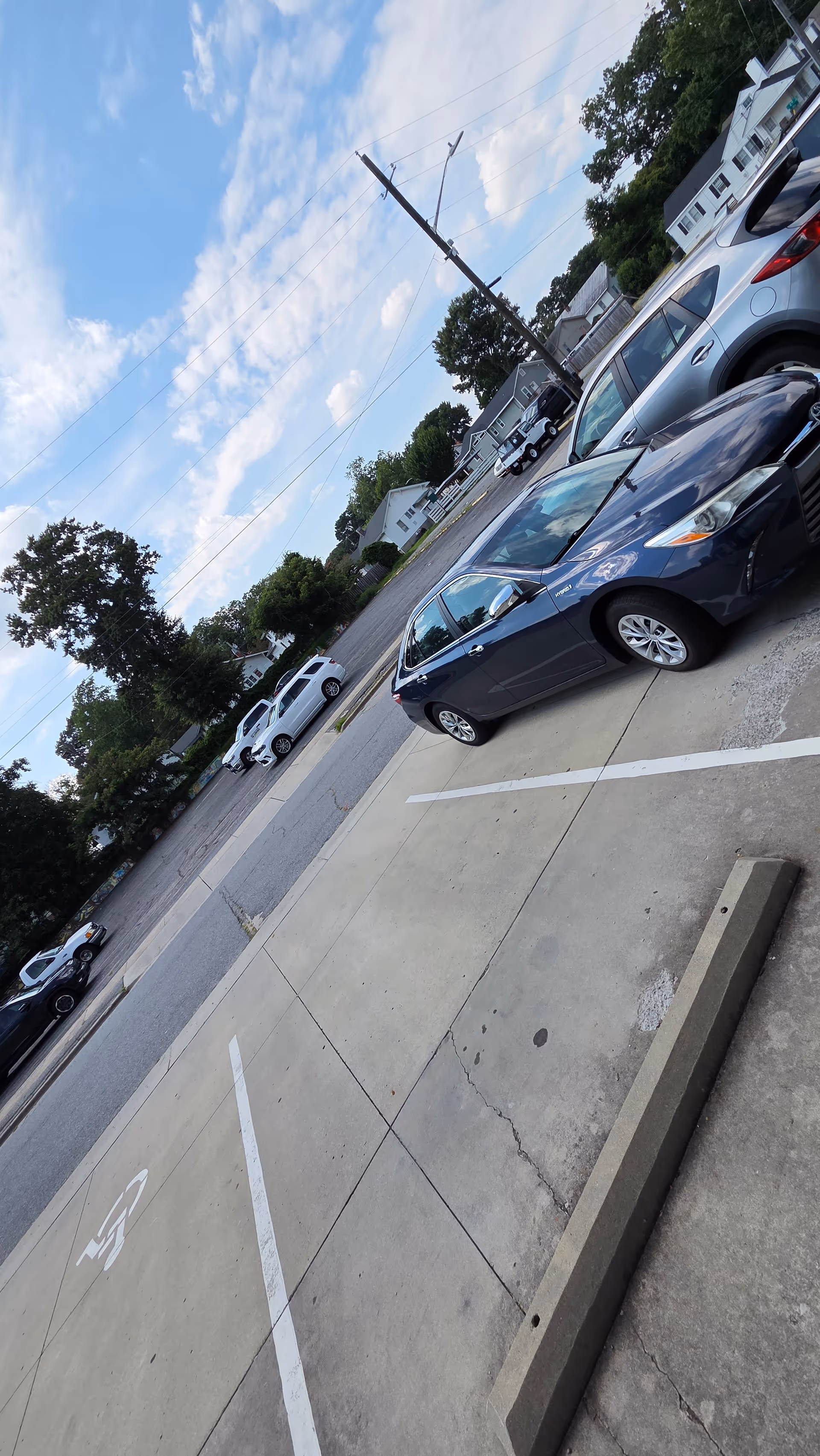 Outdoor parking lot with parked cars and utility pole in front of a building.