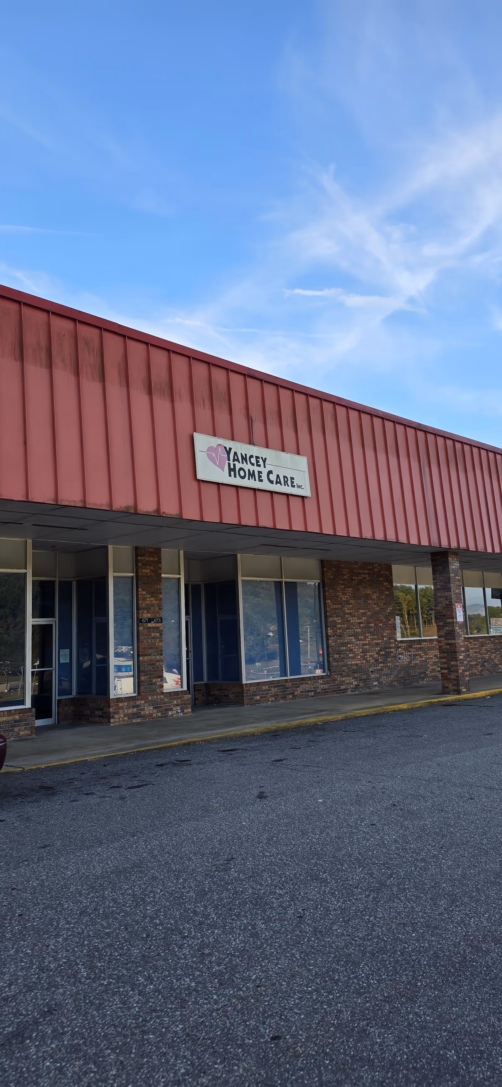 Exterior view of Yancey Home Care building with red roof and sign.