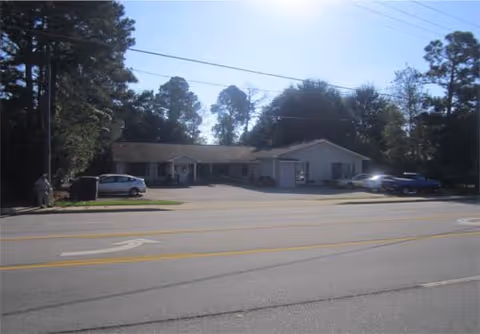Exterior view of Willow Creek Assisted Living building with parked cars along the road.