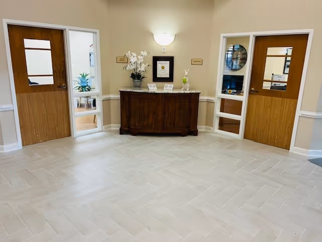Beige lobby with a central dark wooden reception desk and two doors.