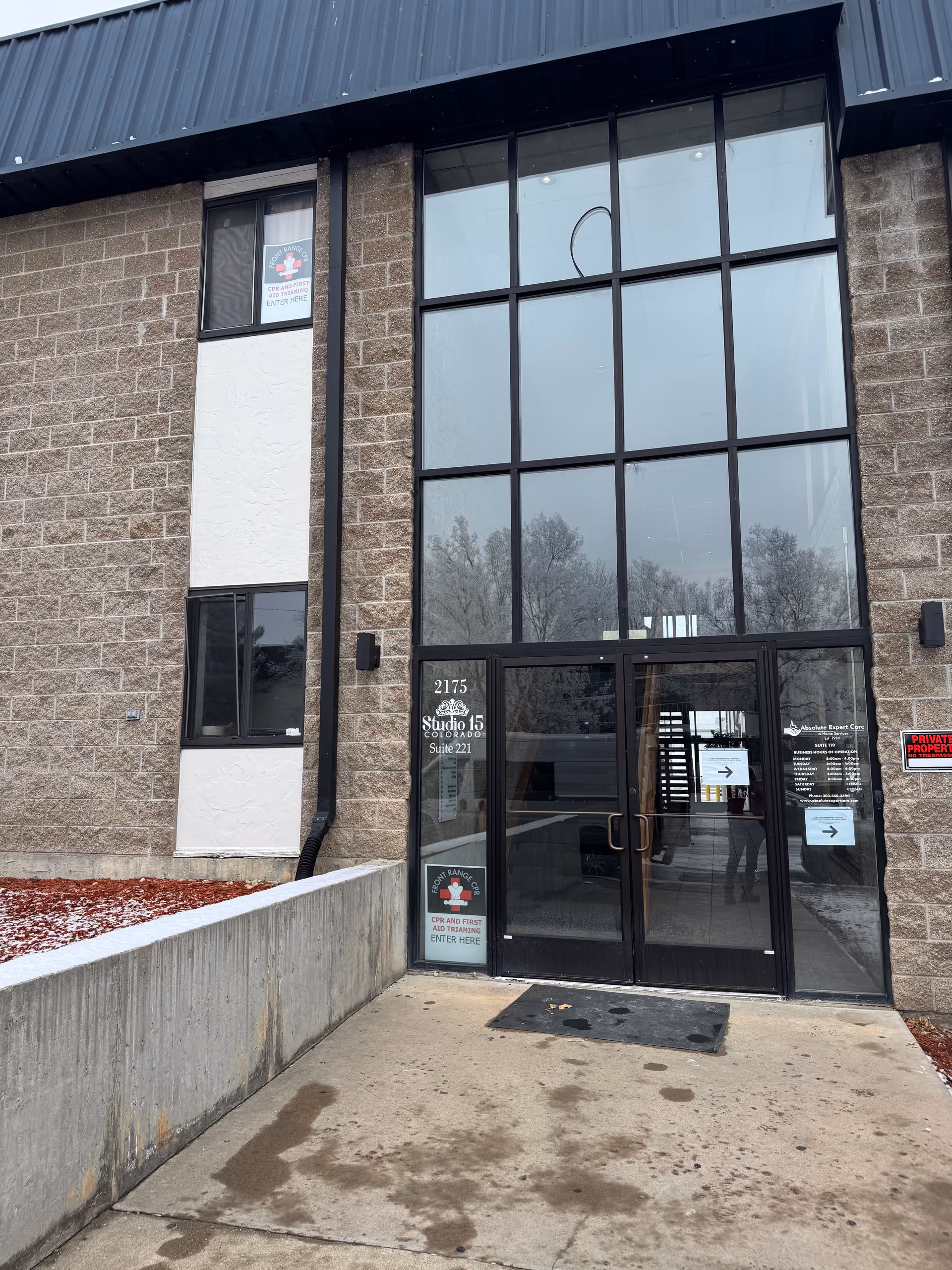 Exterior view of Absolute Expert Care building entrance with large glass doors and brick facade.