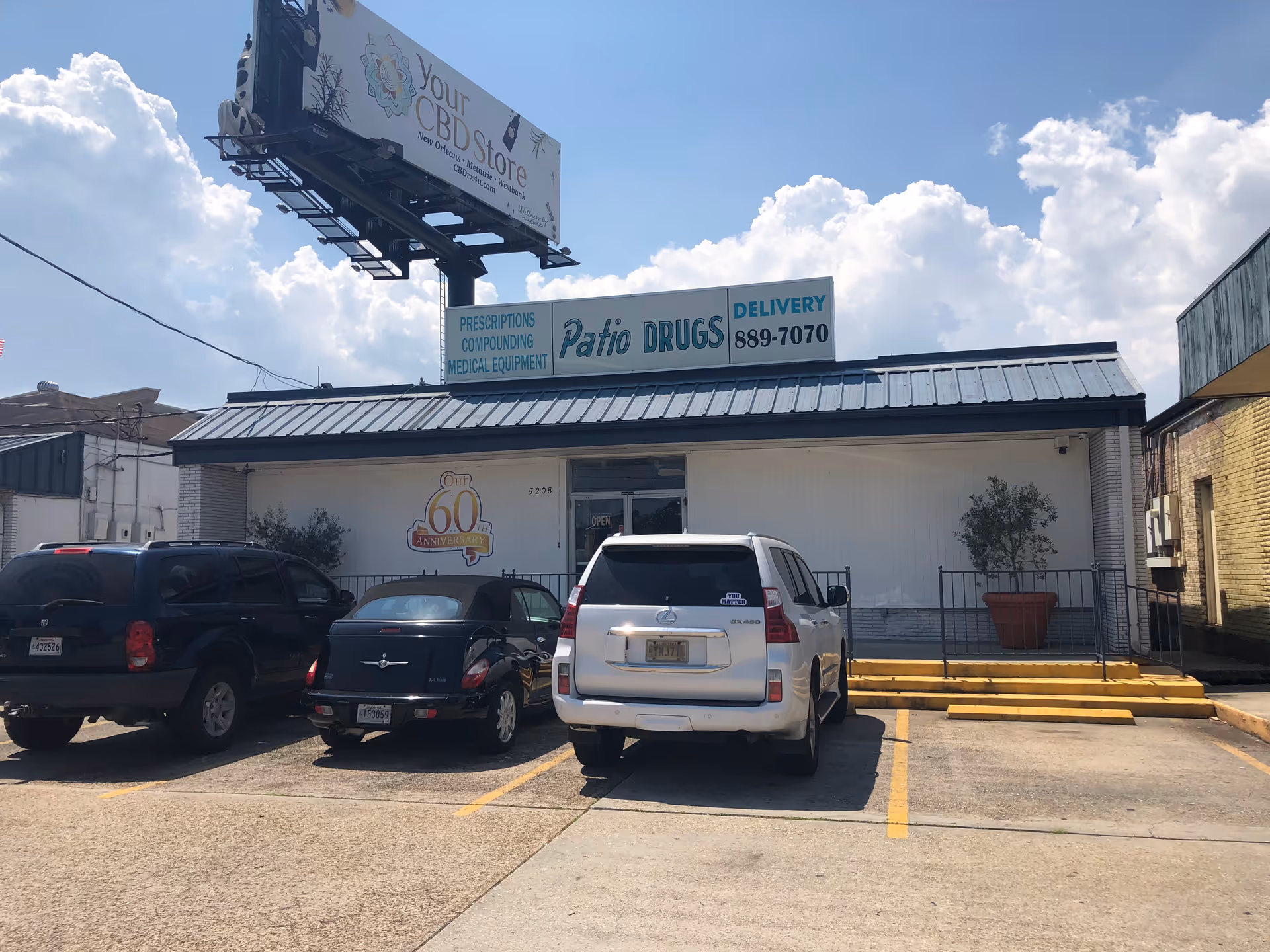 Front exterior of Patio Drugs storefront with multiple cars parked in lot.
