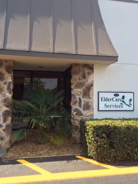 Exterior entrance of ElderCare Services with stone columns, a palm plant, and a sign.