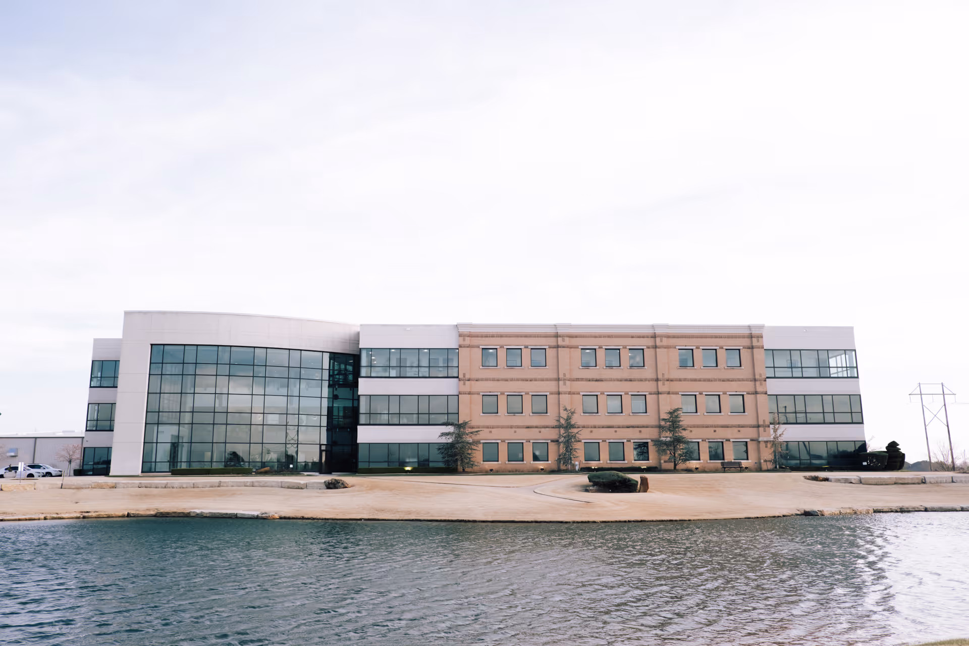 Modern two-story healthcare building with glass facade beside a waterfront, no people.