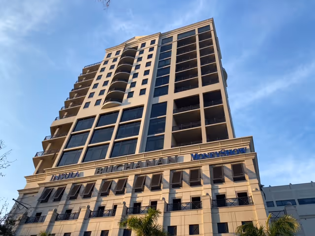 Tall modern high-rise building exterior with balconies and large windows.