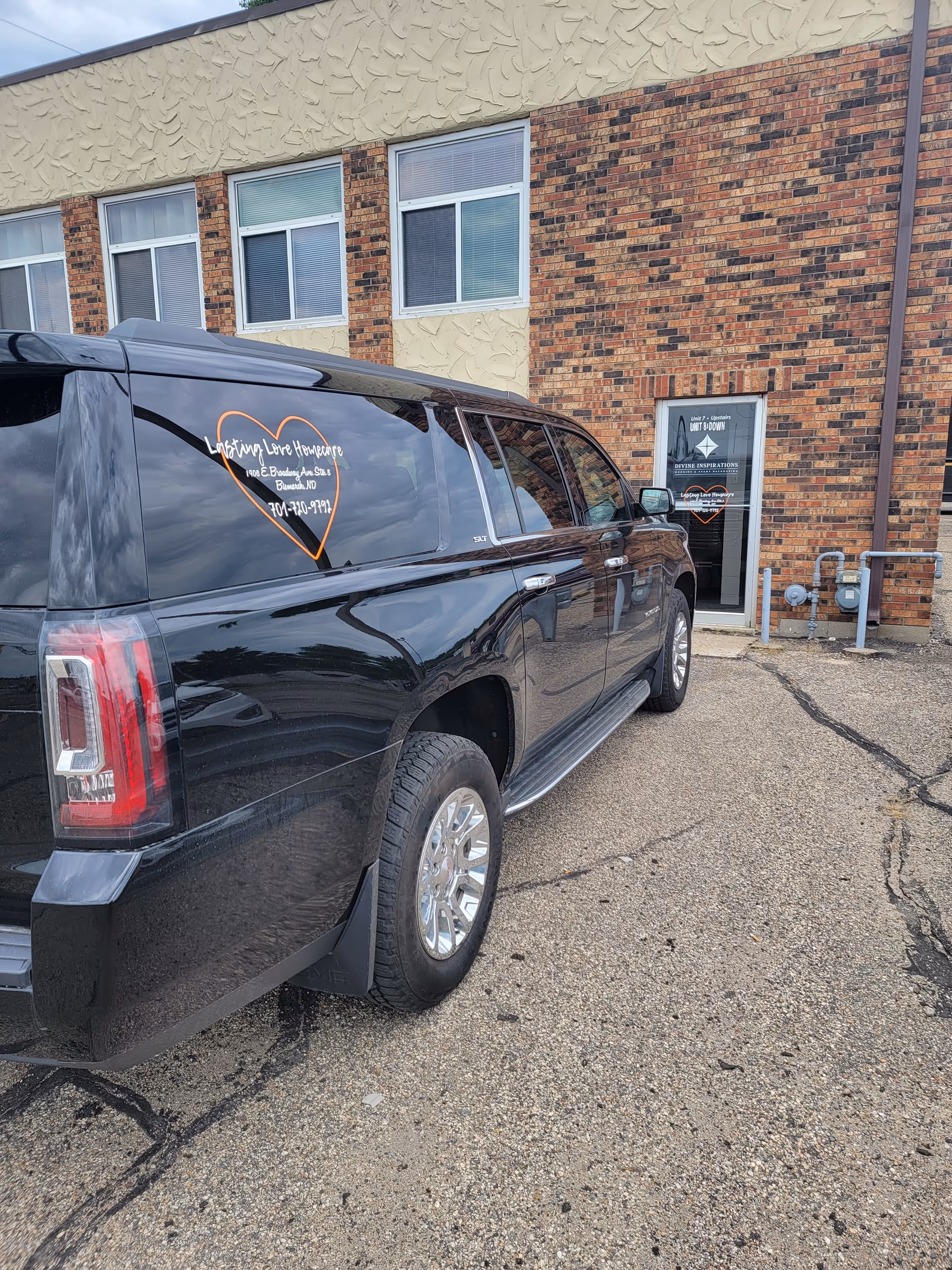 Black van with Lasting Love Homecare logo parked outside a brick senior facility.